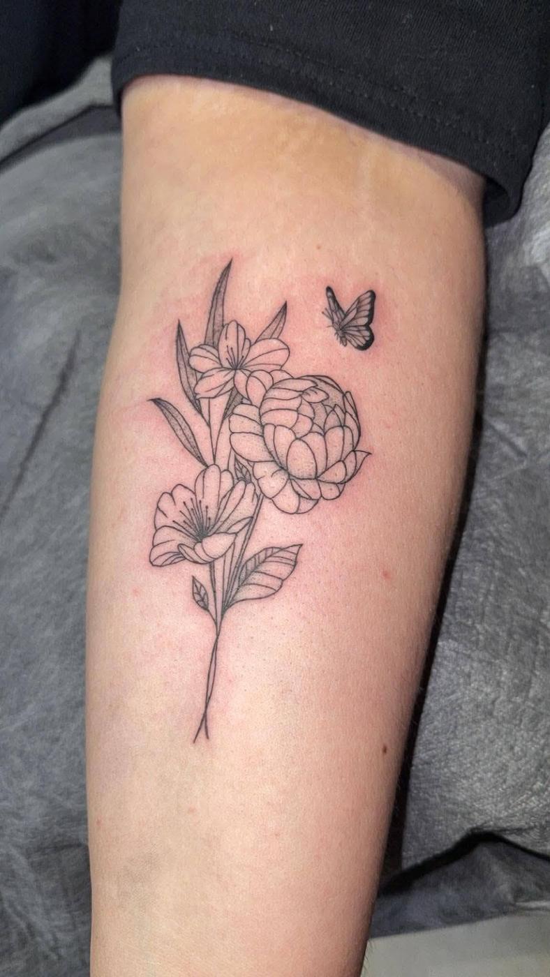 A spray of peonies and lilies with a small butterfly, tattooed in fine single-needle line work on a forearm.